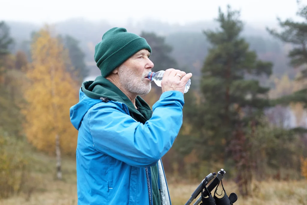 Senior man staying hydrated to maintain oral health during outdoor activities, as advised by Montana Center for Implants and Dentures.