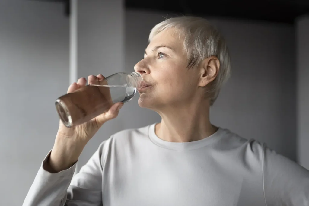 Elderly woman staying hydrated after dental implant surgery, crucial for healing during the first stage of dental implant healing, provided by Montana Center for Implants and Dentures.