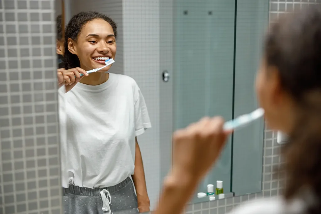 A woman brushing her teeth as part of an oral health routine to combat dry mouth, guided by Montana Center for Implants and Dentures.