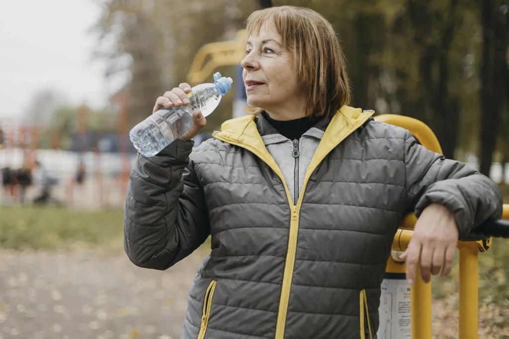 An older woman staying hydrated to prevent dry mouth, a key factor in maintaining oral health, as recommended by Montana Center for Implants and Dentures.